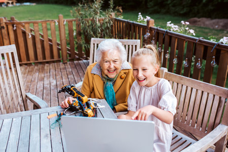 Grandmother supporting granddaughter in robotics, science, IT technologies and programming. Young...