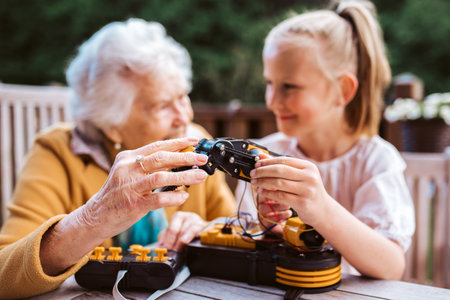 Grandmother supporting granddaughter in robotics, science, IT technologies and programming. Young...