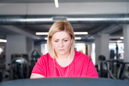 Overweight woman exercising on treadmill in gym.