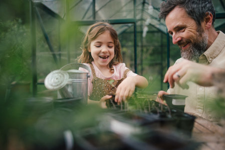Fater and girl working together in garden, planting seedlings, spending time togeter, have shared hobby. Fatherhood and Fathers Day concept.の写真素材
