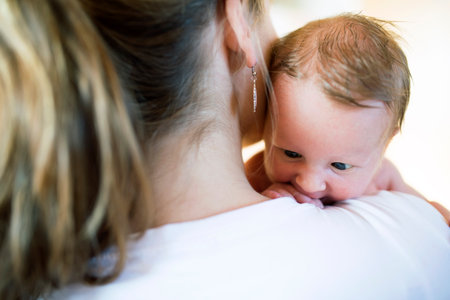 Mom holding newborn baby, looking at infant lovingly. Unconditional paternal love, Mothers Day...