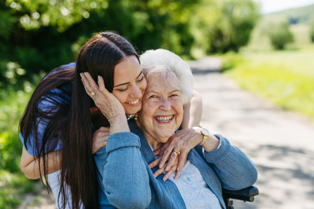 Female caregiver pushing senior woman in wheelchair. Nurse and elderly woman enjoying a warm day in nursing home, public park.の写真素材