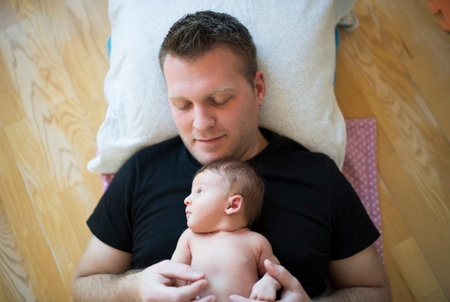 Father holding newborn baby on his chest. Unconditional paternal love, Fathers Day concept.