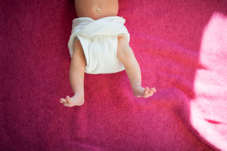 Portrait of legs of little newborn baby lying on bed, wearing diaper.の写真素材