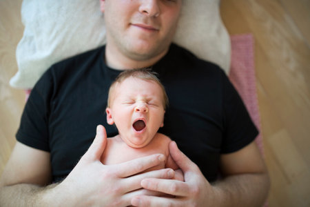 Father holding yawning newborn baby on his chest. Unconditional paternal love, Fathers Day concept.の写真素材