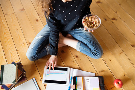 Female student sitting on floor, reading books, studying for final exam at university. Productive...