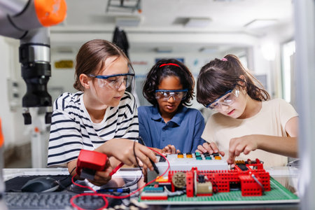 Classmates working togeter on circuit board, building robot in after-school robotics club. Children...