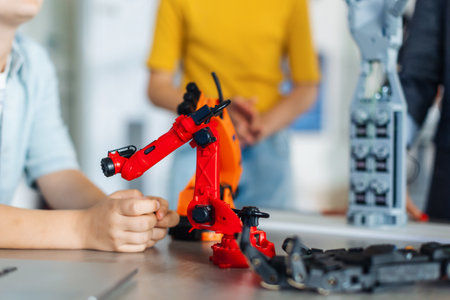 Close up on children looking at small robot, learning robotics in elementary school. Young students building robot in after school robotics club.の写真素材