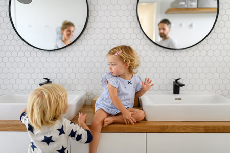 Parents and kids having morning bathroom routine, brushing teeth and washing face, enjoying together time.の写真素材