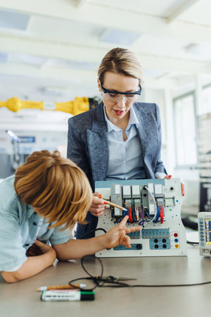 Female teacher explaining circuit board to schoolboy in after-school robotics club. Children learning robotics in Elementary school. Science for kids.の写真素材