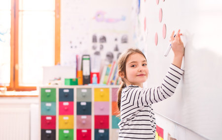 Girl student writing on whiteboard in classroom.の写真素材