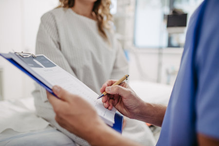 Doctor talking with worried patient before surgery, writing medical document. Emotional support before surgery. Friendly male doctor reassuring patient.の写真素材