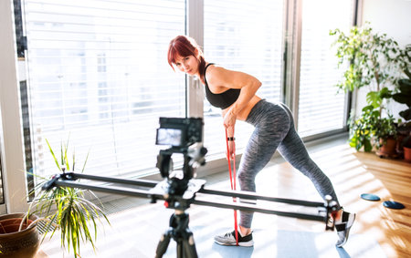 Beautiful redhead woman making video of her workout routine. Online personal trainer.の写真素材