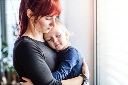 Mother holding toddler, carrying him around house. Unconditional paternal love, mothers Day concept.の写真素材