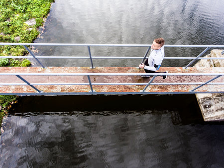 Aerial view of a runner running across bridge in park on a jogging path. Morning running training.の写真素材