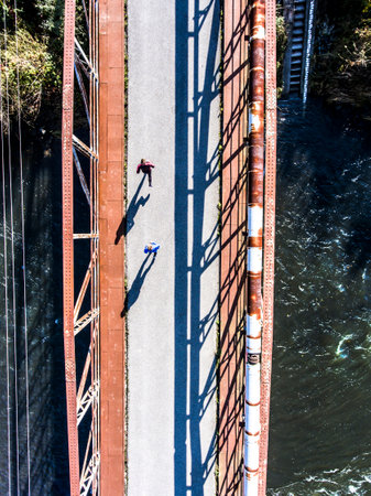 Aerial view of a runner running across bridge over the river. Morning running training.
