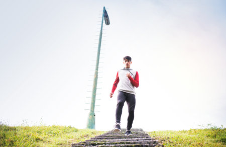 Male runner jogging in park on running trail, down the stairs. Morning running training for young...