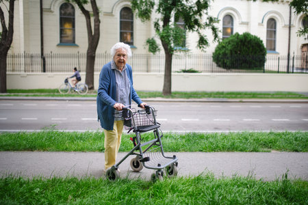 Beautiful elderly woman walking on city street with rollator, going shopping to the store.の写真素材
