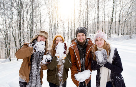 Group of friends on a walk in the snowy nature, holding snowballs . First snowfall of the season.の写真素材