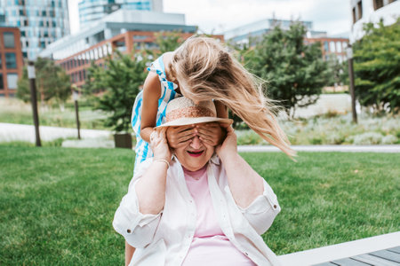 Girl covering grandmas eyes with hands. Granddaughter spending time with senior grandmother, during...