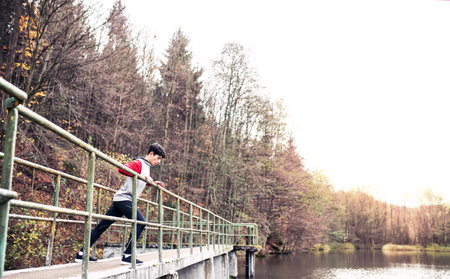 Sporty man preparing for run, stretching in park by lake. Morning workout for young man.の写真素材