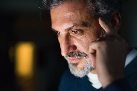 Portrait of handsome man working on laptop. Screen glow illuminates mans face. Telecommuting and home office.の写真素材