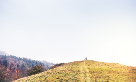 Active man on bike on top of small hill. Resting in the middle of beautiful nature, early autumn morning. Minimalistic, Concept of healthy lifestyle.の写真素材