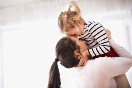 Beatiful young mother holding little daughter in the air, touching with noses.の写真素材