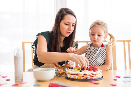 Mom and daughter preparing birthday party, making, decorating birthday cake.の写真素材