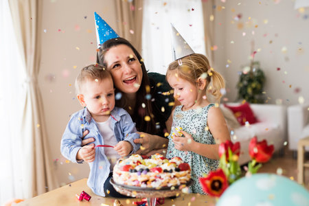 Birthday party with confetti and birthday cake. Mom and two kids having surprise birthday party.
