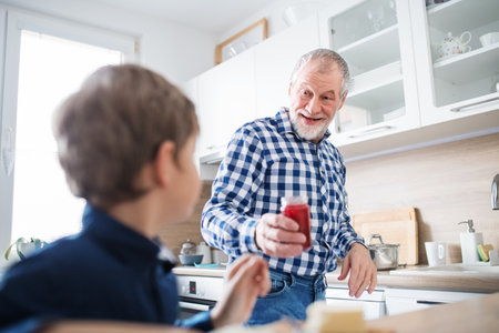 Boy and grandpa making breakfast in the kitchen. Grandfather spending time with grandson, taking...