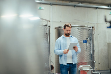 The winemaker standing in the wine cellar, monitoring the fermentation and aging processes in large...