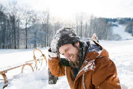 Portrait of man with head injury after snowball fight. Man sitting on ground, snow stuck to clothes and beard.の写真素材