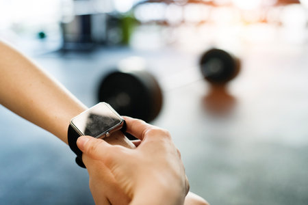 Young fitness girl checking her performance on smartwatch after hard workout in gym.の写真素材