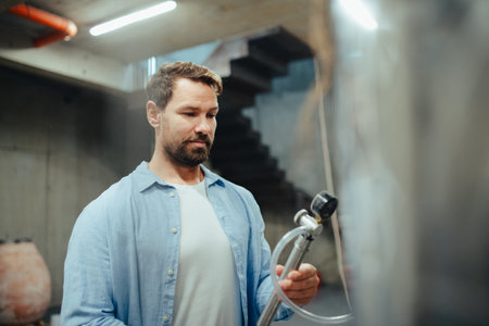 Winemaker standing in the wine cellar, controlling pressure in fermentation tank.