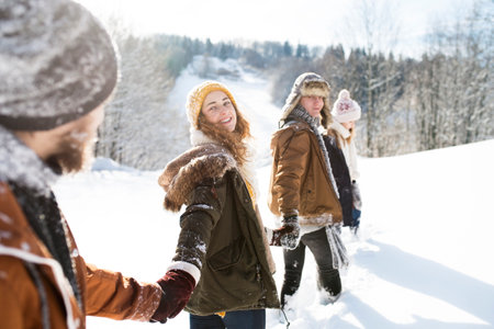 Group of friends on a walk in the snowy nature. First snowfall of the season.の写真素材