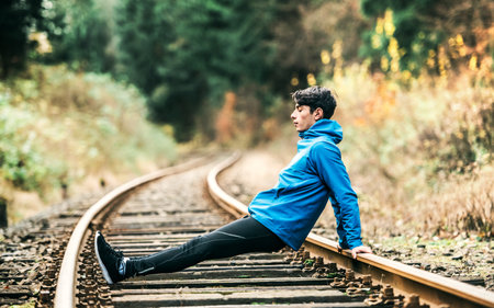 Sporty man exercising on old unused rails in the middle of nature. Morning workout for young man.