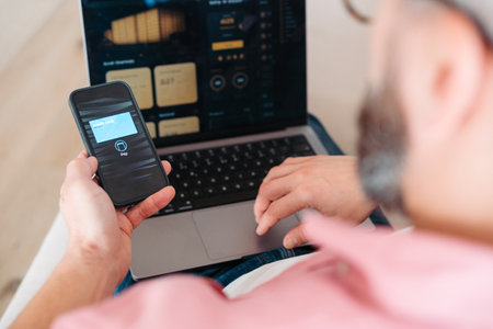 Man with notebook and smartphone sitting on sofa, online banking, internetbanking at home throught...