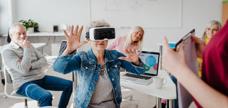 Group of seniors with VR goggles on computer and technology education class. Elderly people learning about virtual reality, using VR headset.の写真素材