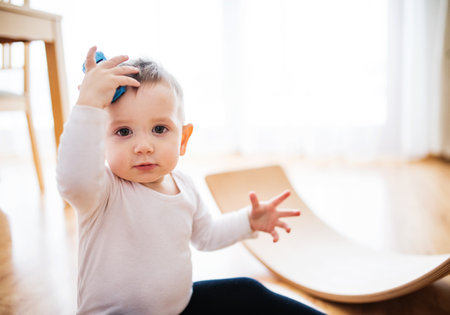 Toddler boy is playing with toy car in living room.の写真素材