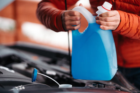 Pouring winter washer fluid into car reservoir during winter, protecting it from freezing.の写真素材