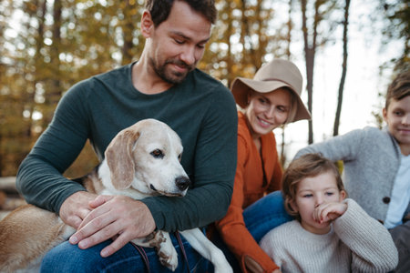 Portrait of family sitting in the middle autumn forest. Nuclear family with dog spending weekend outdoors.の写真素材
