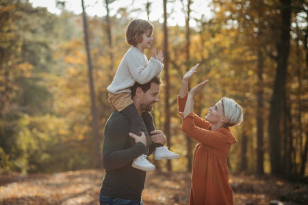 Young family with small children on walk in autumn forest. Father carrying daughter on his...