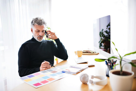 Homeoffice for handsome man. Man working in his office in home, making phone call. Telecommuting.