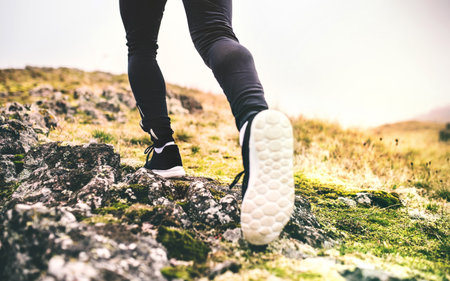 Close up of runners legs, feet with running shoes durig off-road jog in nature on dirt running...