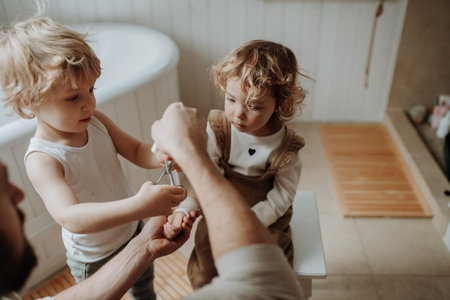 Father is bandaging his daughters injured wrist in bathroom, concentrating while using a bandage.の写真素材