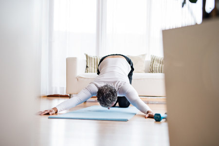 Handsome man exercising at home on gym mat. doing yoga, stretching. Routine home workout for a...