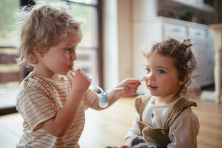 Boy using nasal suction bulb to clear mucus from sisters nose.