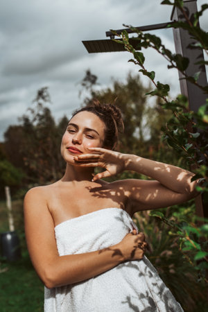 Beautiful woman touching her face, stainding outdoor in the garden. Woman taking care of her body and mind, wellness routine.の写真素材