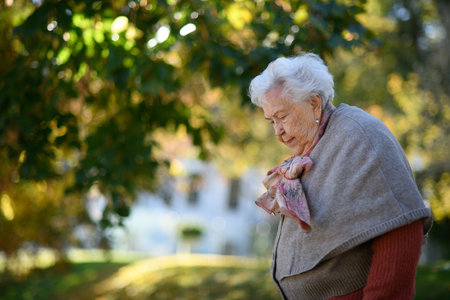 Portrait of elderly woman on walk in the park during warm autumn day.の写真素材